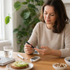 Persoon meet thuis cholesterol met een cholesterolmeter aan de keukentafel.