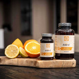 Verschillende formaten Kala Health Ester-C Vitamine C flessen naast vers gesneden citrus