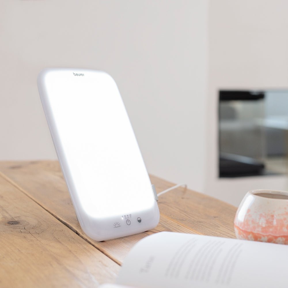 Beurer TL 35 daglichtlamp op houten tafel naast boek en mok