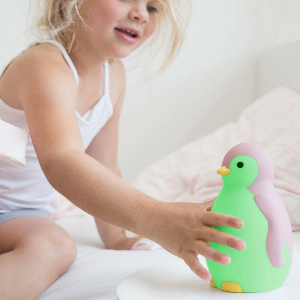 Groene Zazu pinguïn slaaptrainer door meisje aangeraakt op bed