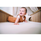 Glimlachende baby op witte matrastopper in wieg