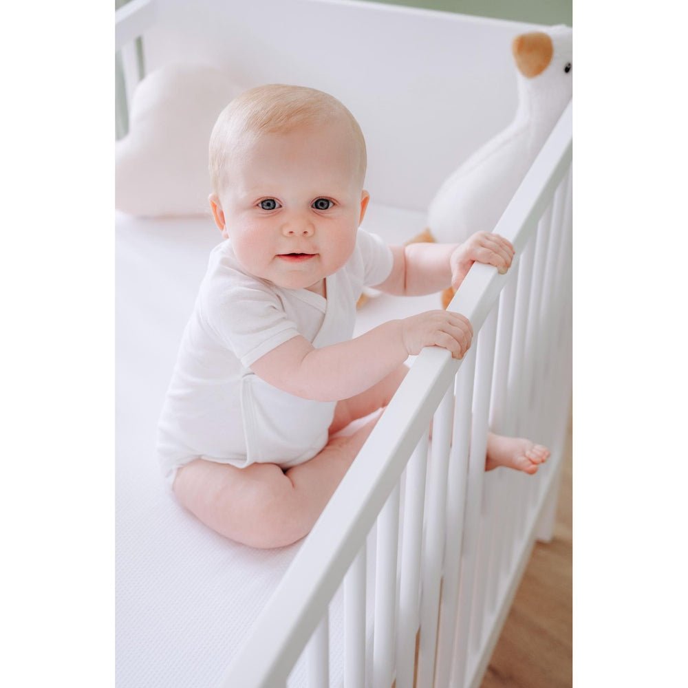 Wit AirgoSafe hoeslaken met mesh-structuur onder babymeisje in wieg