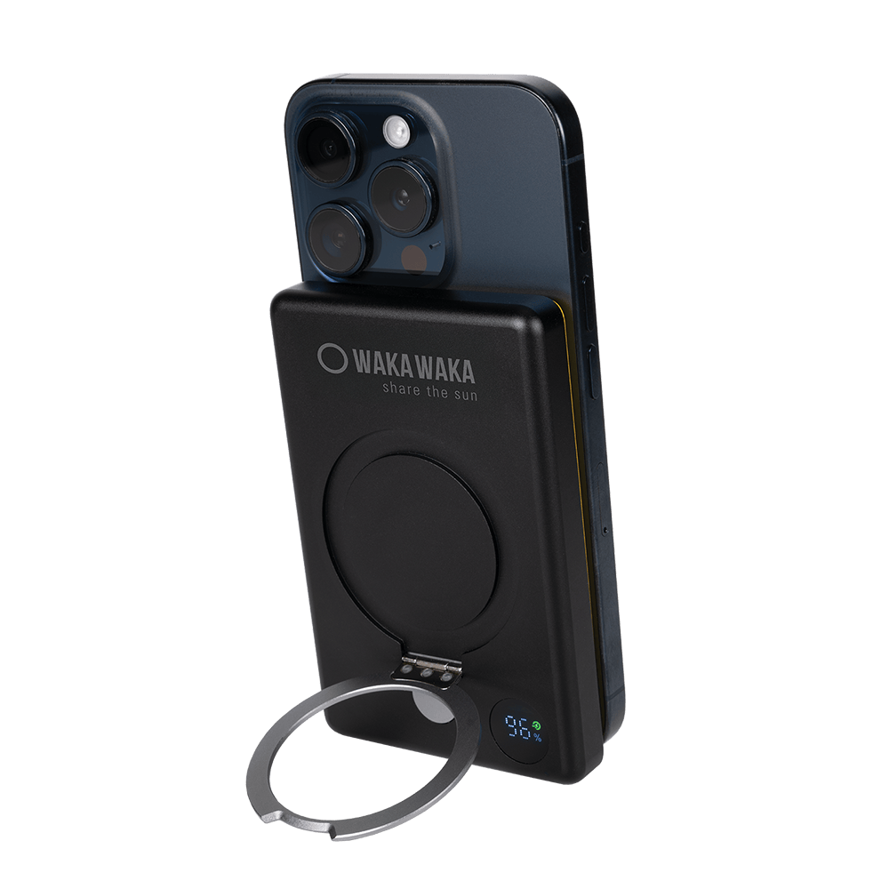 Zwarte Waka Waka powerbank met LED-display en kickstand bevestigd aan smartphone