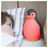Roze Zazu pinguïn nachtlampje naast slapend kind op houten bed