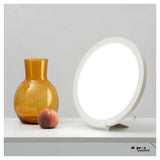 Innolux Rondo Air daglichtlamp in gebruik op bureau naast decoratieve vaas