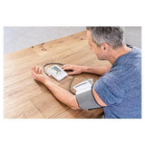 Beurer BM51 bloeddrukmeter met grijze voorgevormde manchet op houten tafel