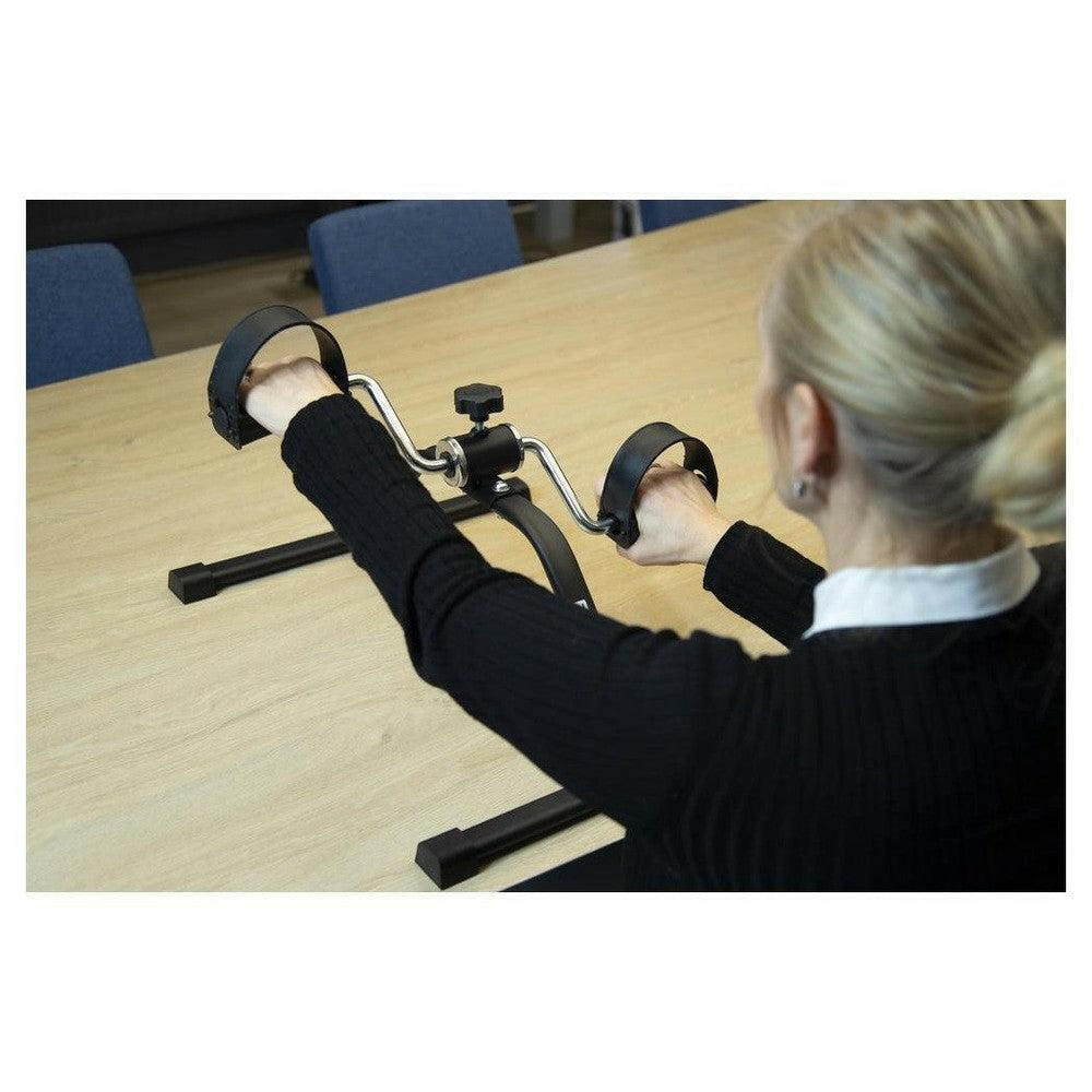 Gebruik Fysic mobiliteitstrainer aan tafel met zilveren handgrepen en zwart frame