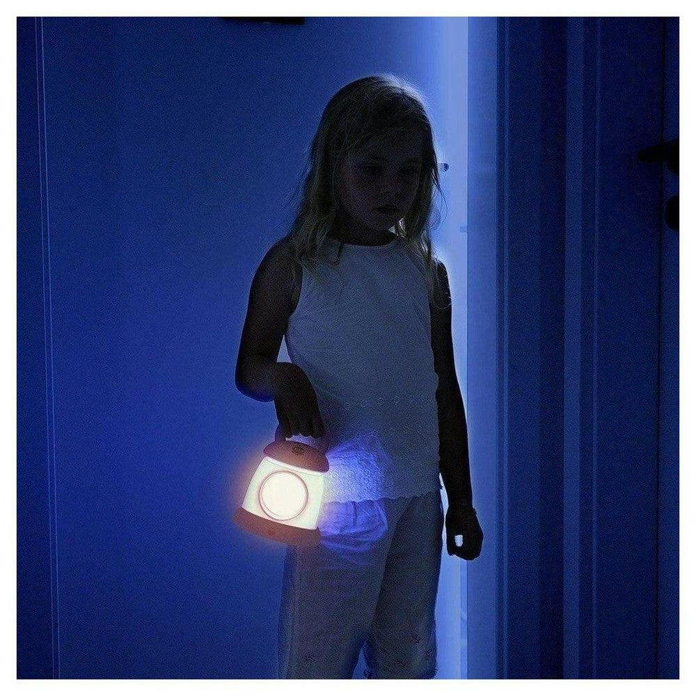 Kind houdt warmwit verlichte Kid'Sleep Lantaarn vast in donkere slaapkamer