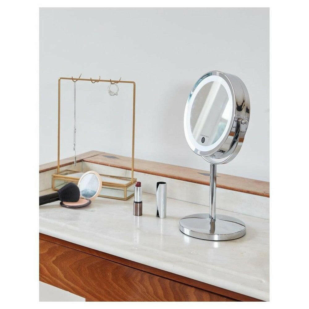 Make-upspiegel op voet met LED-ring en chroomconstructie naast sieraden en cosmetica