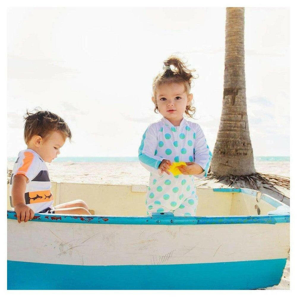 Kind draagt Snapper Rock UV-zwemkleding met stippen in boot op strand