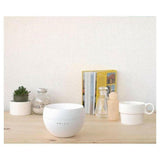 Witte aroma diffuser op houten oppervlak met groen plantje en decoratieve elementen