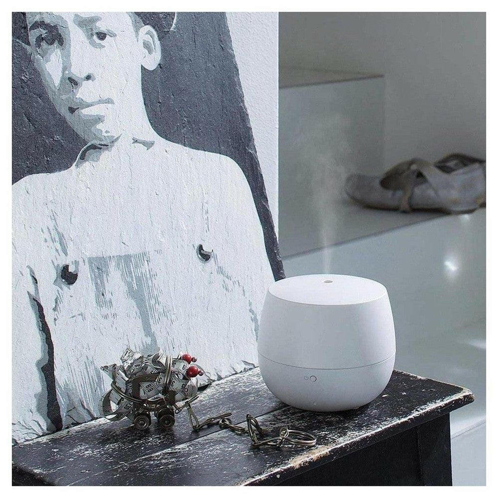 Witte aroma diffuser in gebruik met zichtbare nevel op houten tafel