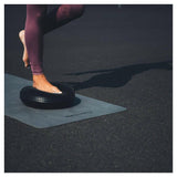 Persoon staat op Tunturi Air Stepper Pad zwart op yogamat voor evenwicht