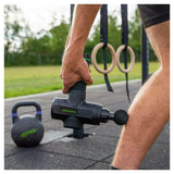 Tunturi massagepistool zwart gebruikt op dij outdoor fitness