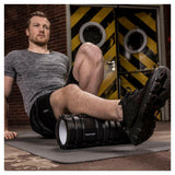 Man gebruikt zwarte Tunturi foamroller voor dijspierverlichting tijdens training