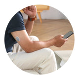 Man draagt CareSens Air glucosesensor op arm en kijkt naar app op smartphone