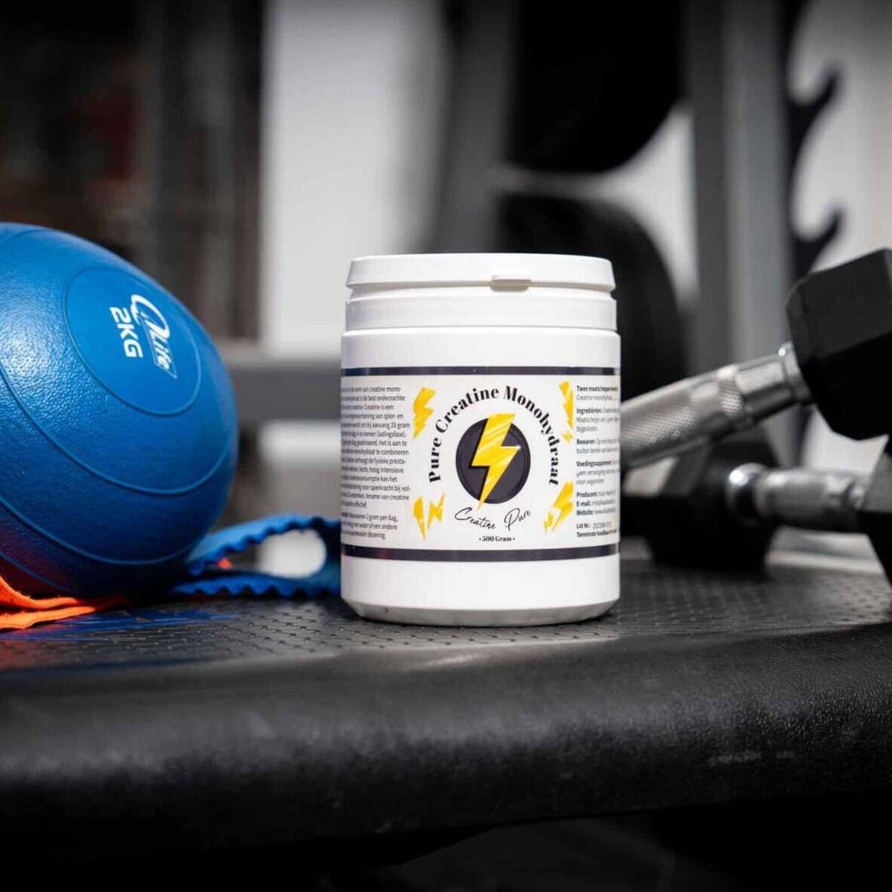Creatine Monohydraat supplement in gymomgeving naast dumbbell en fitnessbal voor spiertraining
