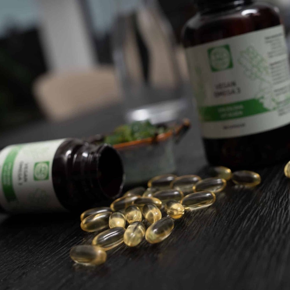 Kala Health vegan omega-3 capsules uit algenolie met EPA en DHA, goudgele capsules op donkere houten ondergrond