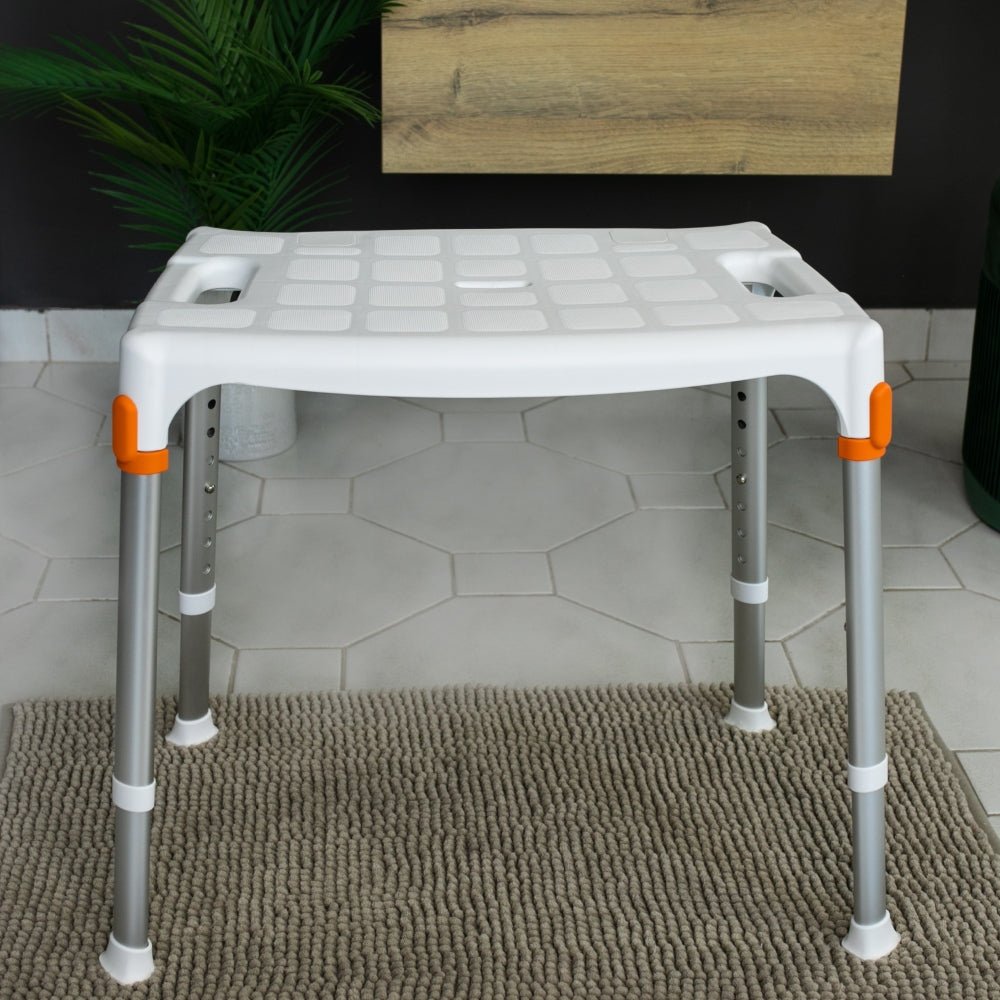Witte douchestoel met handgrepen op textuurmat in moderne badkamer