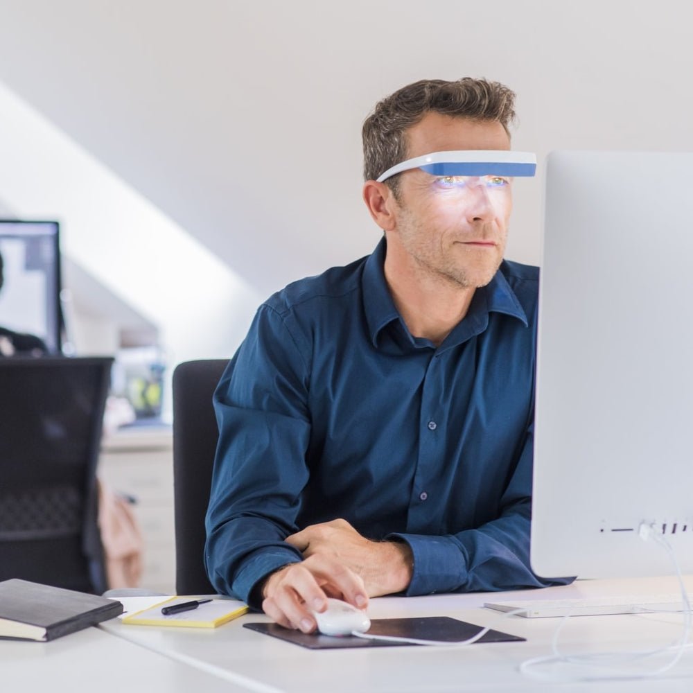 Man gebruikt Luminette 3 lichttherapiebril tijdens werk aan bureau tegen jetlag