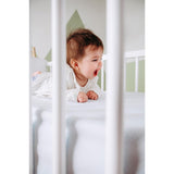 Baby slaapt op wit AirgoSafe hoeslaken met geperforeerde textuur in wieg
