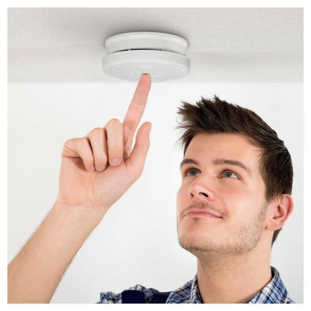 Man test witte Alecto rookmelder aan het plafond met TEST/HUSH knop