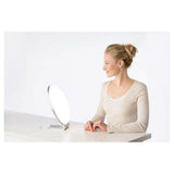Vrouw gebruikt Beurer TL50 daglichtlamp op witte tafel tegen winterblues