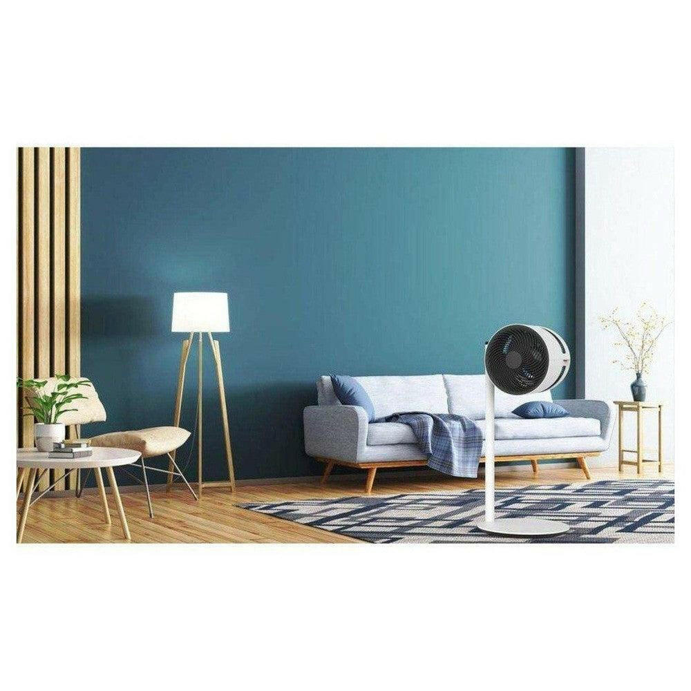 witte ventilator in woonkamer met donkerblauwe muur, grijze bank en geometrisch tapijt