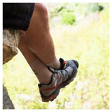 Beige wandelsokken gedragen door persoon op rots met Salomon schoenen in naturomgeving