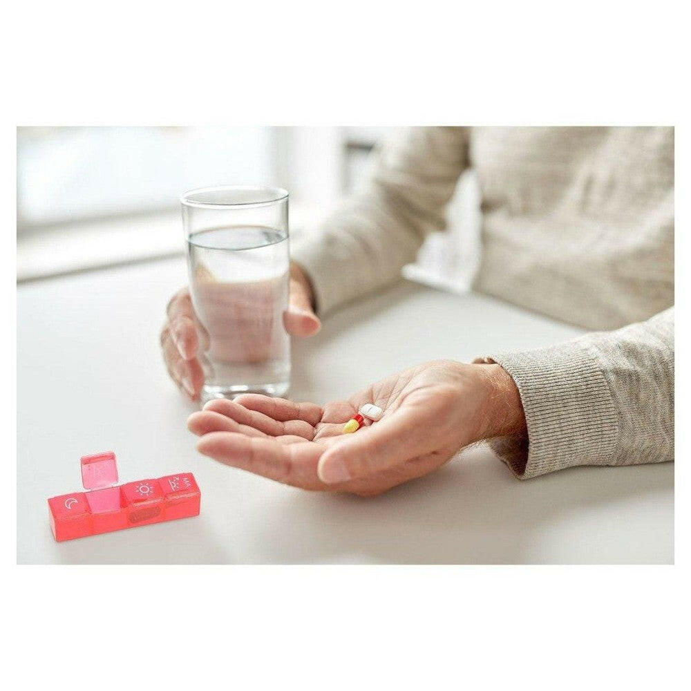 Persoon neemt medicijnen naast roze Fysic pillendoosje
