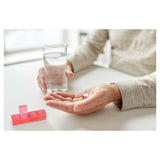 Persoon neemt medicijnen naast roze Fysic pillendoosje