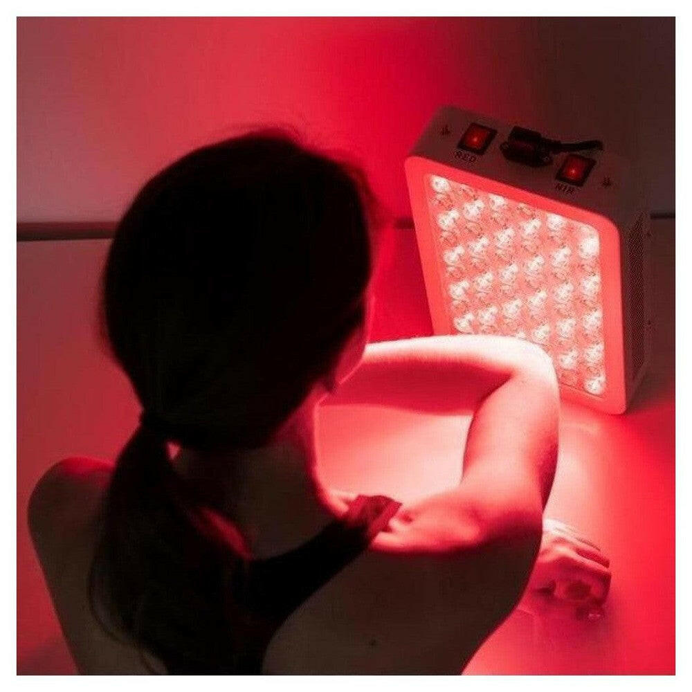 Infraroodlamp in gebruik voor armbehandeling met rode LED-gloed