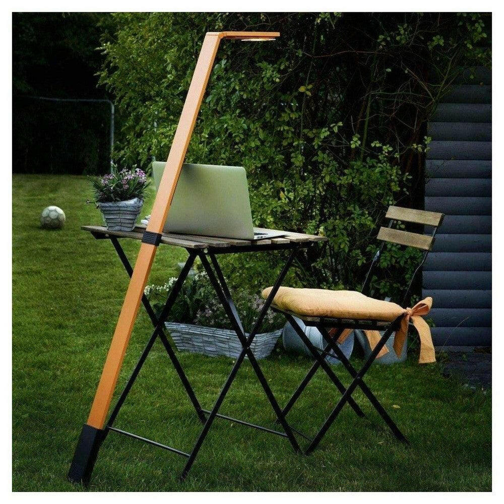 Oranje LED-lamp verlicht laptop op vouwtafel in tuin