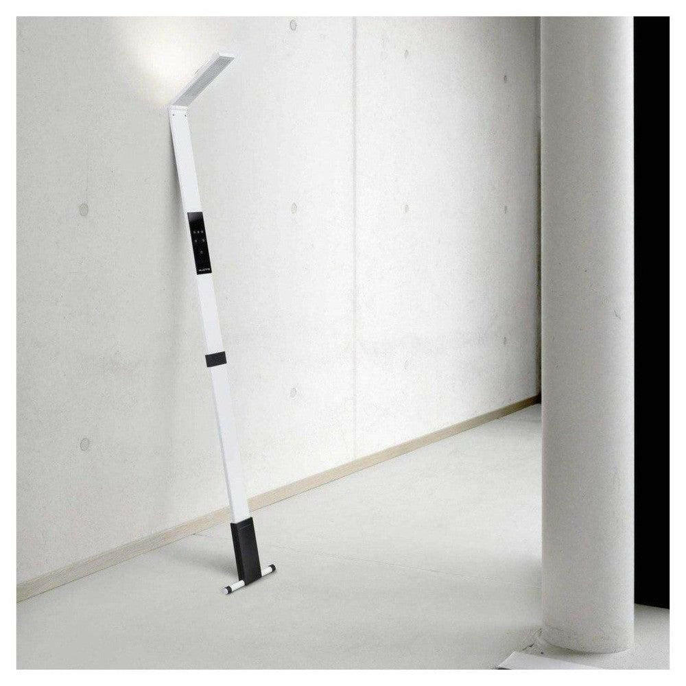 Witte staande LED-lamp met T-voet tegen betonnen muur
