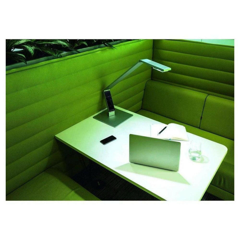 Grijze Luctra Linear bureaulamp die helder licht werpt op werkplek met laptop