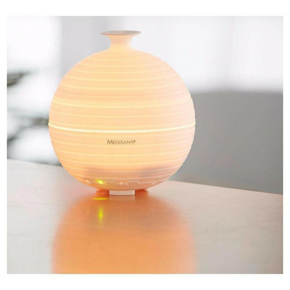 Medisana AD 620 aroma diffuser wit met oranjegele sfeerverlichting op houten tafel