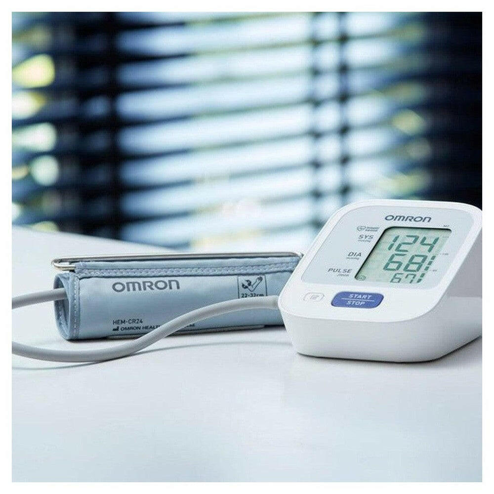 Omron M2 bloeddrukmeter met lichtblauw manchet maat 22-32cm op wit oppervlak