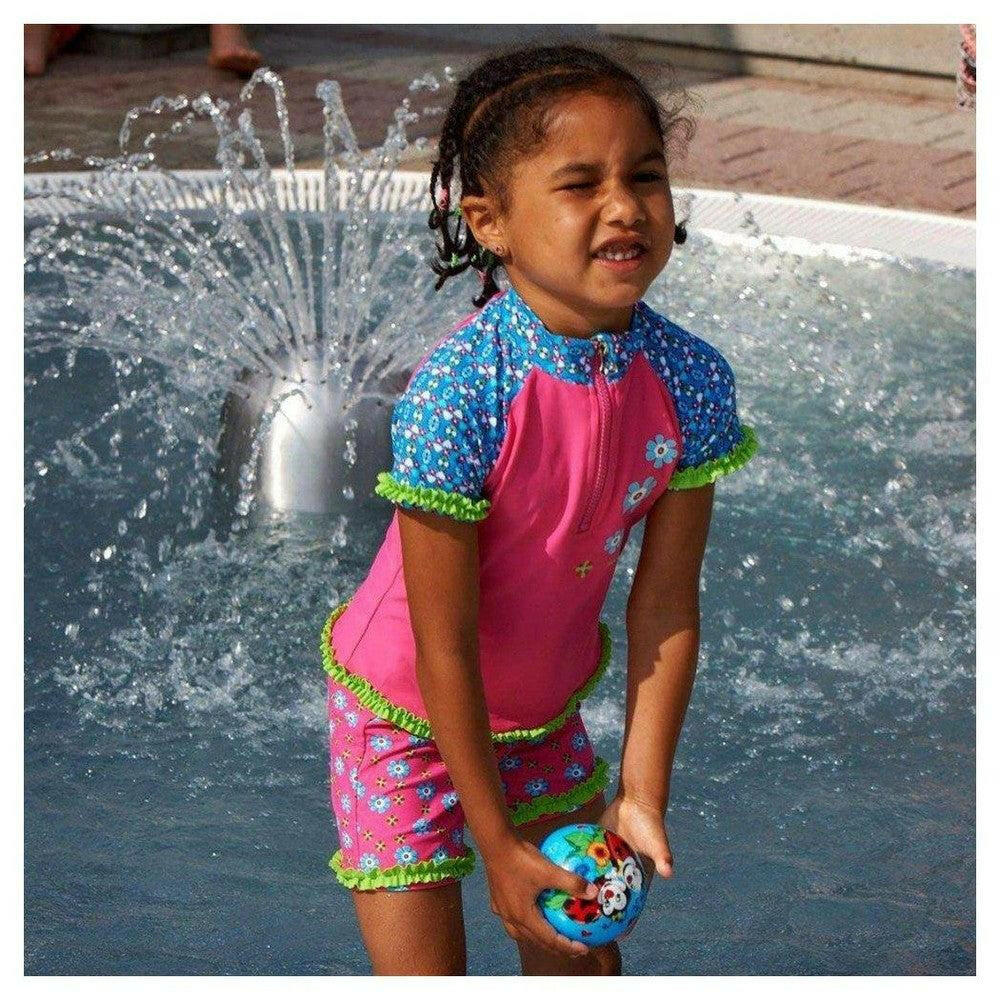 Roze Playshoes UV-zwemkleding set met bloemenprint voor meisjes, getoond in een waterfontein