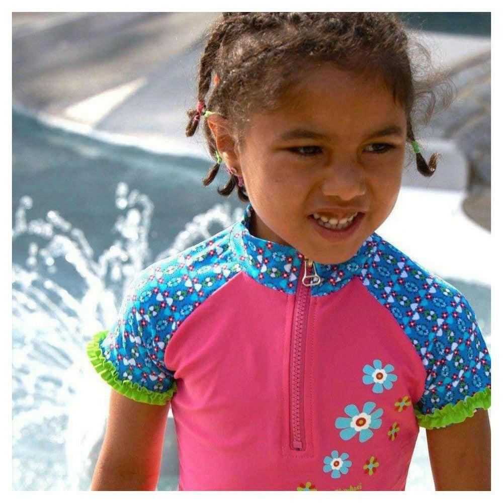 Close-up van roze Playshoes zwemkleding met bloemenprint en groene ruches aan de zoom