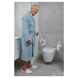 Man gebruikt uitklapbare toiletbeugel voor steun bij wc