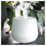 Witte Stadler Form Julia aroma diffuser met vijf zilveren knoppen op donkere tafel