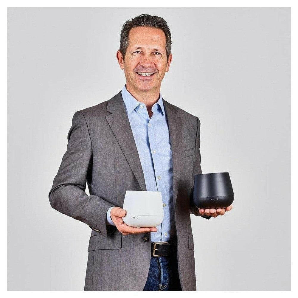 Handen houden witte en zwarte Stadler Form Julia aroma diffusers ter vergelijking