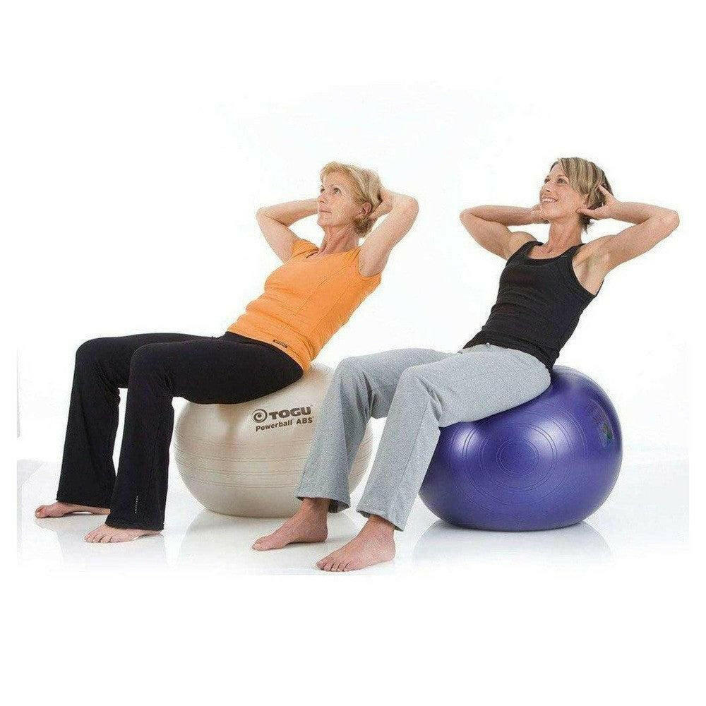Twee vrouwen doen buikspieroefeningen op beige en paarse fitnessballen