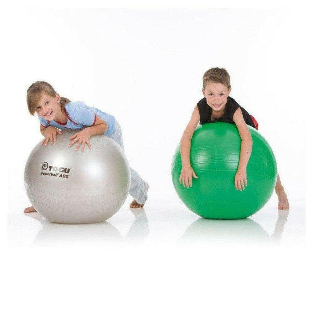 Kinderen poseren naast zilveren en groene Togu Powerball fitnessballen