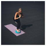 Vrouw mediteert op Tunturi Air Stepper Pad blauw op paarse yogamat