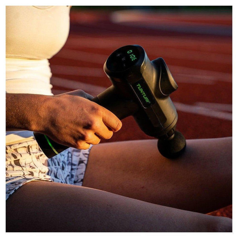 Tunturi massagepistool digitaal scherm gebruikt op atletiekbaan